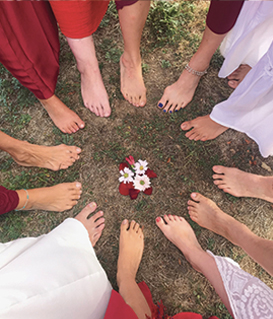 Photo de fleurs entourées par les pieds de plusieurs femmes présentes lors d'une retraites assurée par Marion Tur, sophrologue & thérapeute en harmonie de conscience à Rodez dans l'Aveyron